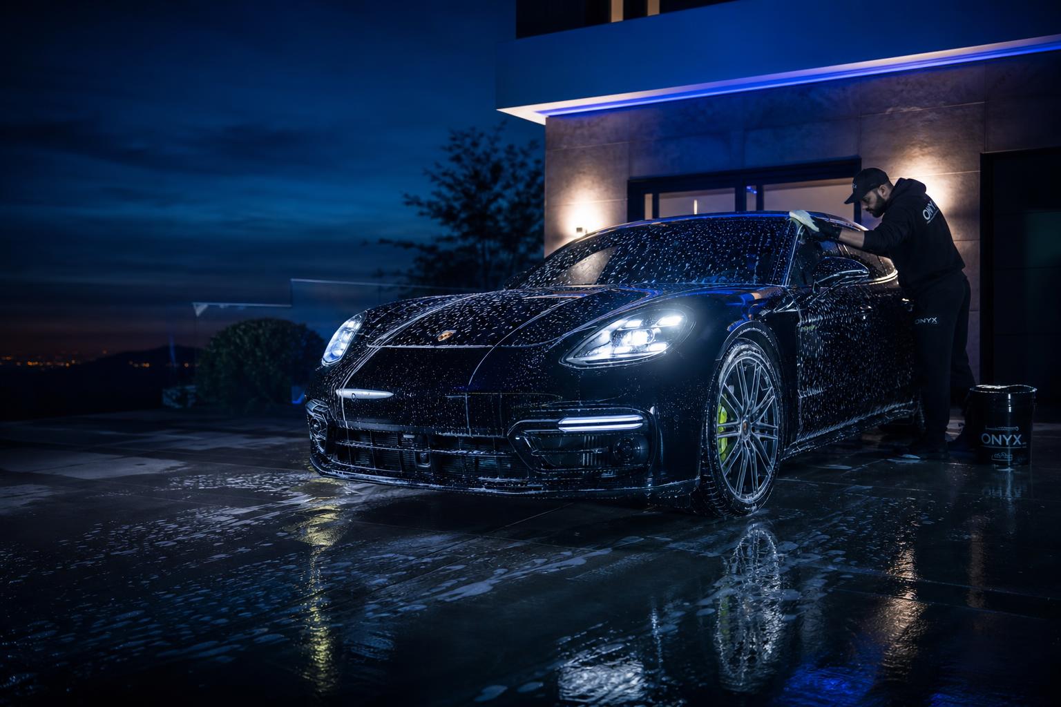 Luxury black Porsche being detailed in a premium driveway